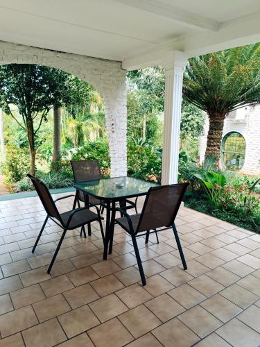 a glass table and chairs on a patio at Pecan Farm Guesthouse in Louis Trichardt