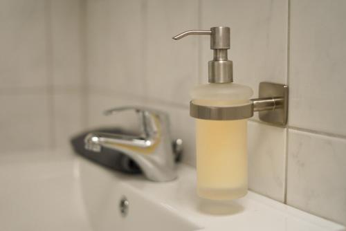 a soap dispenser on a sink next to a faucet at Möblierte 3-Zimmer-Wohnung nahe Düsseldorf in Duisburg-Süd in Duisburg