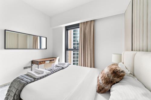 Luxury 2 Bedroom Apartment - Next to Dubai Opera في دبي: غرفة نوم بيضاء مع سرير كبير ونافذة