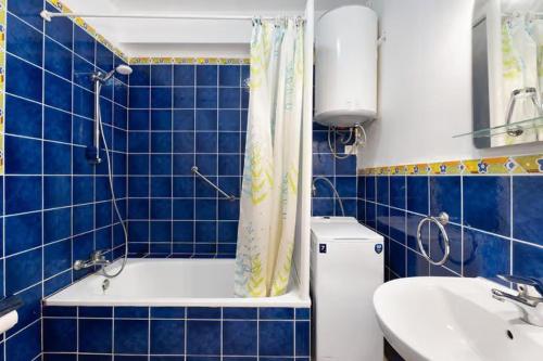 W wyłożonej niebieskimi kafelkami łazience znajduje się wanna i umywalka. w obiekcie 001, club atlantis, puerto colon, adeje w Adeje