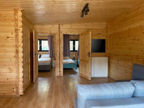sala de estar con paredes de madera, sofá y TV en Toscana Camp, en Pogorzelica