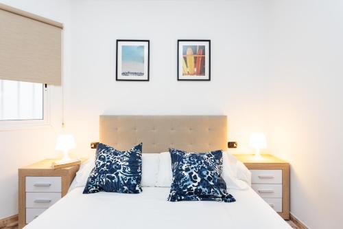 Un dormitorio con una cama blanca con almohadas azules. en Vivienda vacacional El Pijaral, en El Roque