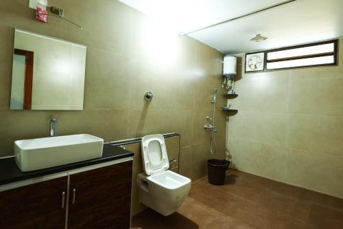 a bathroom with a toilet and a sink and a mirror at Panchavati Villa in Manipala