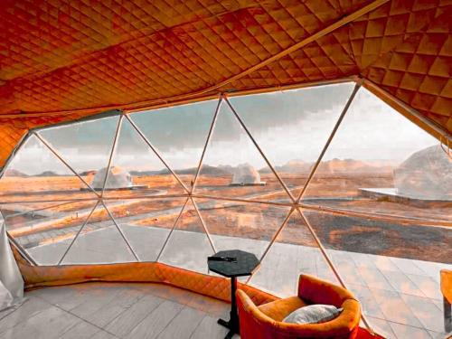 een kamer met uitzicht op de woestijn door een glazen wand bij Traditions of Wadi Rum camp & jeep tour in Wadi Rum