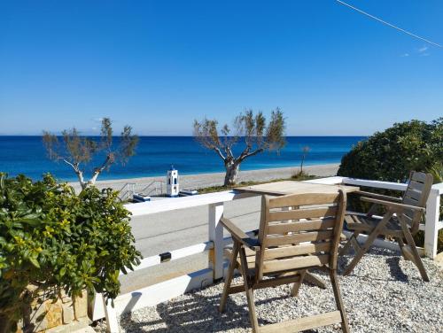 a table and chairs on a beach with the ocean at ILIOPOULOS Apartments in Mourteri