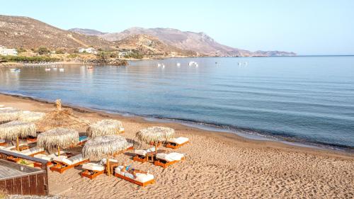 a beach with chairs and straw umbrellas and the water at Maria Beach Hotel in Kissamos