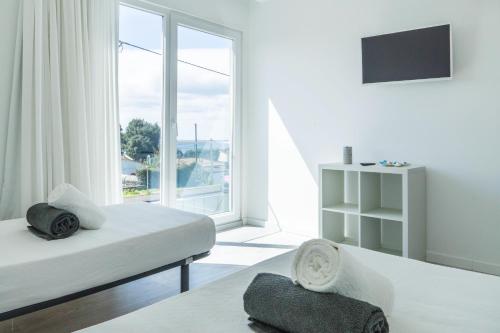 a white room with two beds and a large window at Beach Front Villa in Ponta Delgada