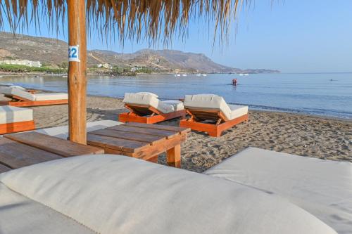 a beach with chaise lounges and chairs on the beach at Maria Beach Hotel in Kissamos
