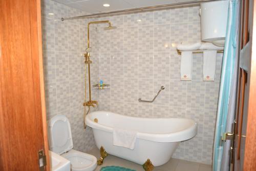 a bathroom with a white tub and a toilet at Adamaoua Grand Hôtel Aéroport in Douala