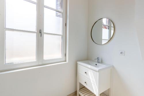 uma casa de banho branca com um espelho e um lavatório em Studio Paon d'Or, 5 minutes du ZooParc de Beauval em Saint-Aignan