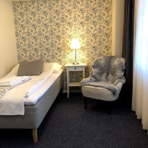 a bedroom with a bed and a chair and a lamp at Ödevata Gårdshotell in Emmaboda