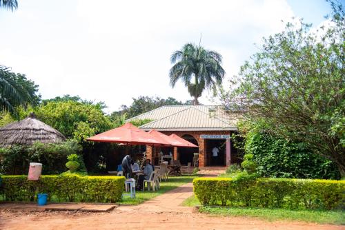 a man sitting at a table in front of a house at New Court View Hotel in Masindi