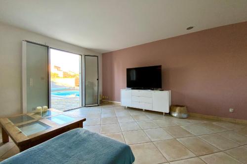 ein Wohnzimmer mit einem Flachbild-TV und einem Sofa in der Unterkunft La Castelnauvienne- 3 bedroom villa with swimming pool! in Castelnau-le-Lez