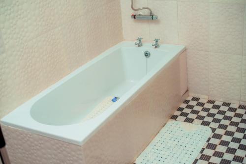 uma banheira branca na casa de banho com piso em azulejo em Hillside Luxury Lodge em Blantyre