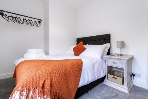 a bedroom with a bed with an orange blanket and a table at Railway Retreat in Wakefield