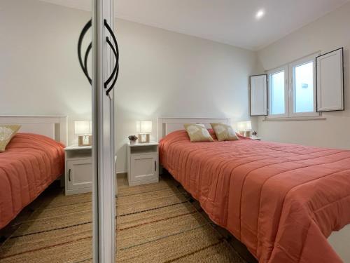 a bedroom with two beds and two windows at A Janela do Conforto in Reguengos de Monsaraz