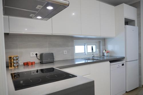 a kitchen with white cabinets and a black counter top at A Janela do Conforto in Reguengos de Monsaraz
