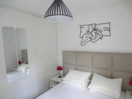 ein Schlafzimmer mit einem weißen Bett und einem Schild an der Wand in der Unterkunft Rez de Jardin T3 recent et calme au Nouvelles Terres à La Londe les Maures in La Londe-les-Maures