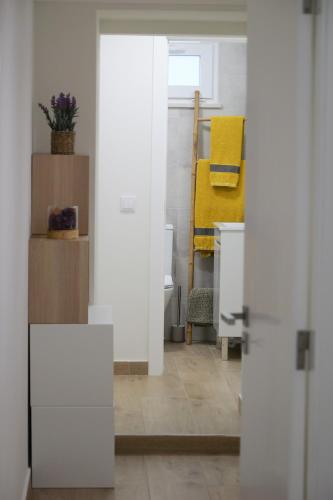 a room with white walls and a yellow chair at A Janela do Conforto in Reguengos de Monsaraz
