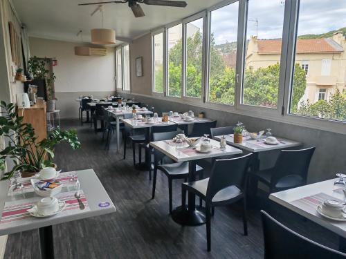 une salle à manger avec tables, chaises et fenêtres dans l'établissement Les Lavandes, à La Ciotat