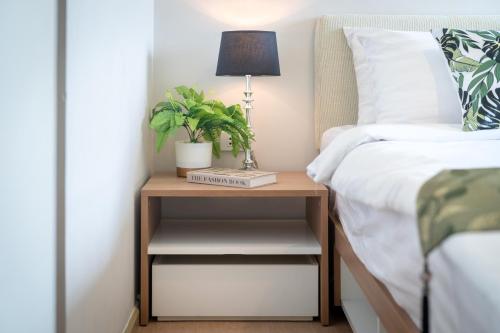 a bedside table with a lamp and a plant on it at ZcapeX2 in Bang Tao Beach