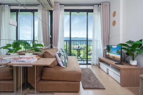 a living room with a couch and a table and a tv at ZcapeX2 in Bang Tao Beach