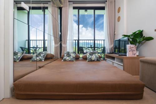a room with two beds and a balcony with windows at ZcapeX2 in Bang Tao Beach
