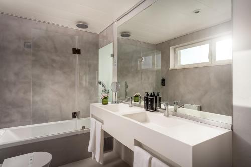 a white bathroom with a sink and a tub at Hotel Baia in Cascais