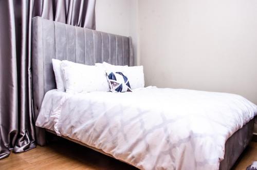 a bed with white sheets and a gray headboard at Keisha Homes in Thika