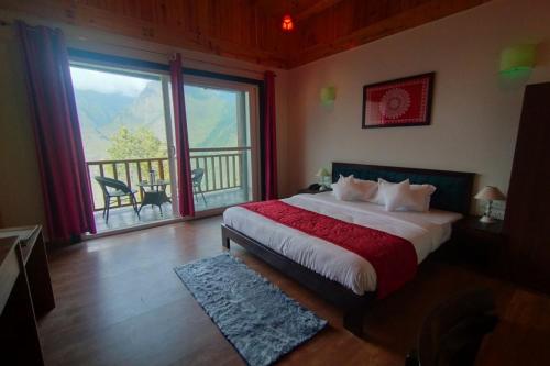 a bedroom with a bed with a view of a balcony at Satine Resort Auli in Joshīmath