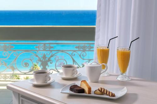 a table with two cups and two drinks and bread at Rodos Palladium Leisure & Wellness in Faliraki