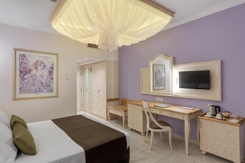 a bedroom with a bed and a desk and a television at Rodos Palladium Leisure & Wellness in Faliraki