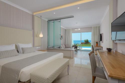 a bedroom with a bed and a desk and a dining room at Rodos Palladium Leisure & Wellness in Faliraki
