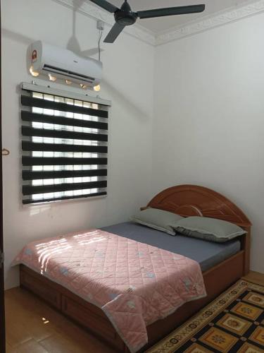 a bedroom with a bed with a fan and a window at Homestay Lembah Tambunan in Kampong Nail
