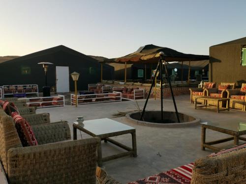 een patio met stoelen en tafels en een parasol bij The Friendly Camp in Zagora