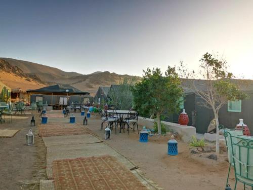 a patio with tables and chairs in the desert at The Friendly Camp in Zagora
