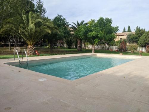 a swimming pool in a park with palm trees at Hotel El Convent 1613 in La Fresneda