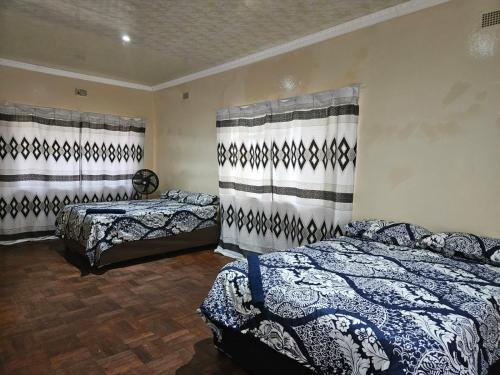 - une chambre avec 2 lits et des rideaux sur le mur dans l'établissement Stay Sunrise, à Nelspruit