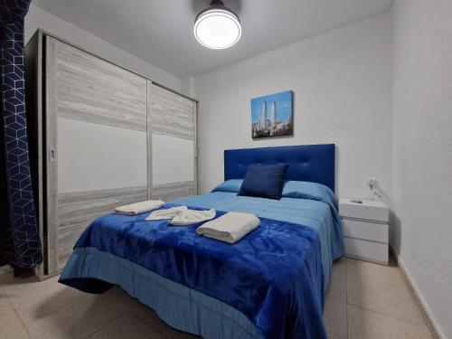 Un dormitorio con una cama azul con toallas. en DICHA 24 en Sevilla