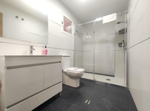 a white bathroom with a toilet and a shower at DICHA 24 in Seville
