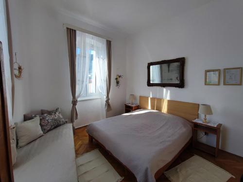 a bedroom with a bed and a window and a couch at APARTMAN RIVA 2 in Komiža