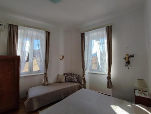 a bedroom with a bed and two windows at APARTMAN RIVA 2 in Komiža