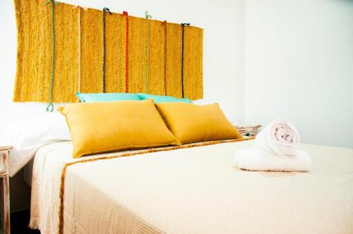 カレタ・デ・ファマラにあるFamara Surfのベッドルーム1室(黄色と青の枕付きのベッド1台付)