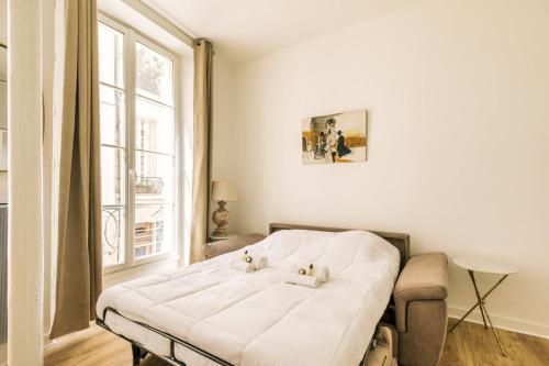 un lit blanc dans une chambre avec une fenêtre dans l'établissement GuestReady - Lovely studio in Paris, 15 minutes from Notre Dame Cathedral., à Paris
