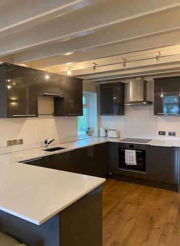 a large kitchen with black cabinets and white counter tops at Contemporary Duplex: Private Patio, Secure Parking in Stockport