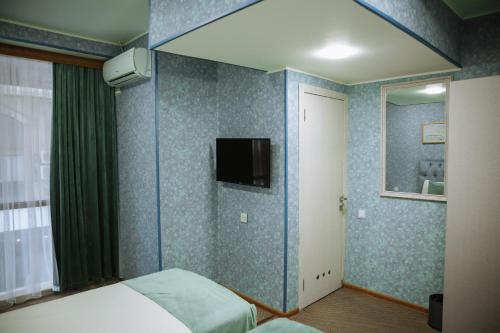 Address Boutique Hotel Baku في باكو: غرفة نوم مع سرير وتلفزيون على الحائط