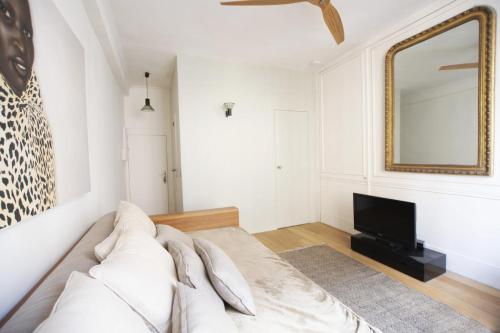 - une chambre avec un lit, un miroir et une télévision dans l'établissement GuestReady - Charmant studio à 10 mins du Louvre, à Paris