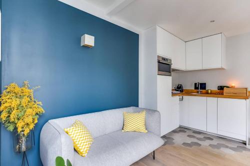 un salon avec un canapé et un mur bleu dans l'établissement GuestReady - Serene 1BR Apt in Folie-Méricourt, à Paris