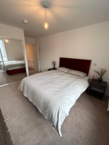 a bedroom with a large white bed and a mirror at Immaculate 2-Bed Apartment in Canning Town in London