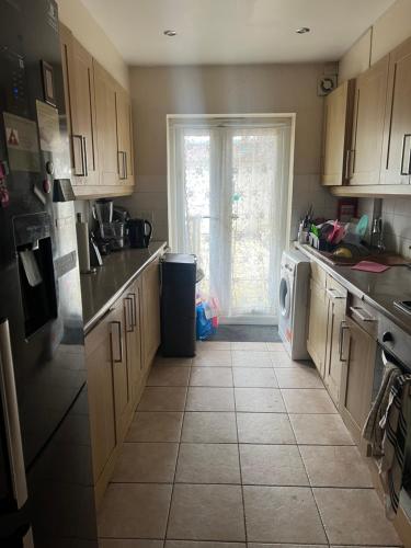 a kitchen with wooden cabinets and a tile floor at Affordable Room to Rent for Short Stay in Abbey Wood